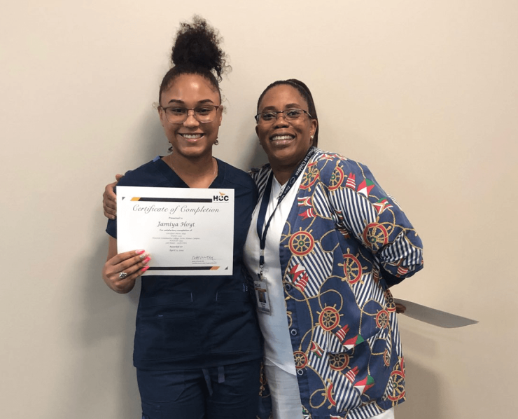A graduate of the ASCEND program stands with an instructor